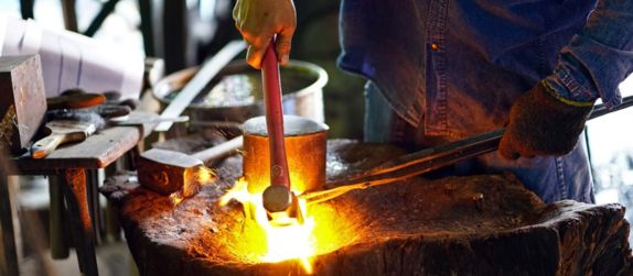 a blacksmith performs metal working at a historical reenactment